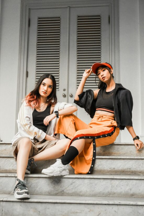 Two fashionable Asian women posing on stairs showcasing modern urban style.